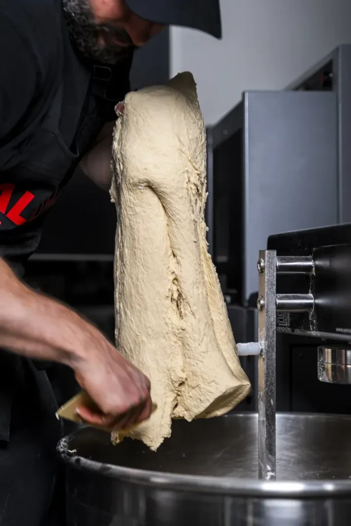 Pizzaïolo sortant la pâte à pizza maison du pétrin